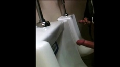 two slim dicks getting wanked at the urinals